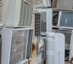 Home A collection of various old and broken air conditioning units piled outdoors.