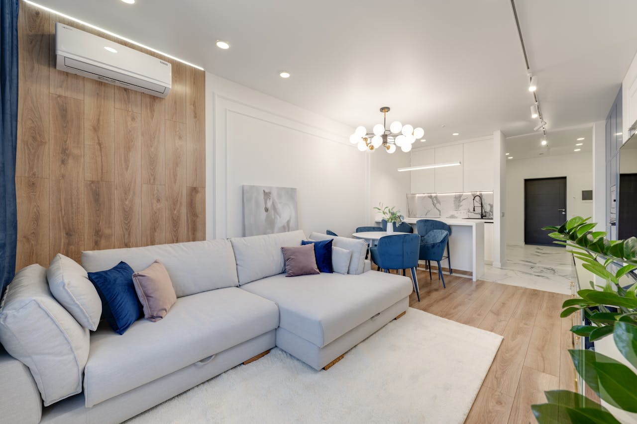 about-01 Contemporary living room with stylish furniture, elegant chandelier, and open kitchenette.