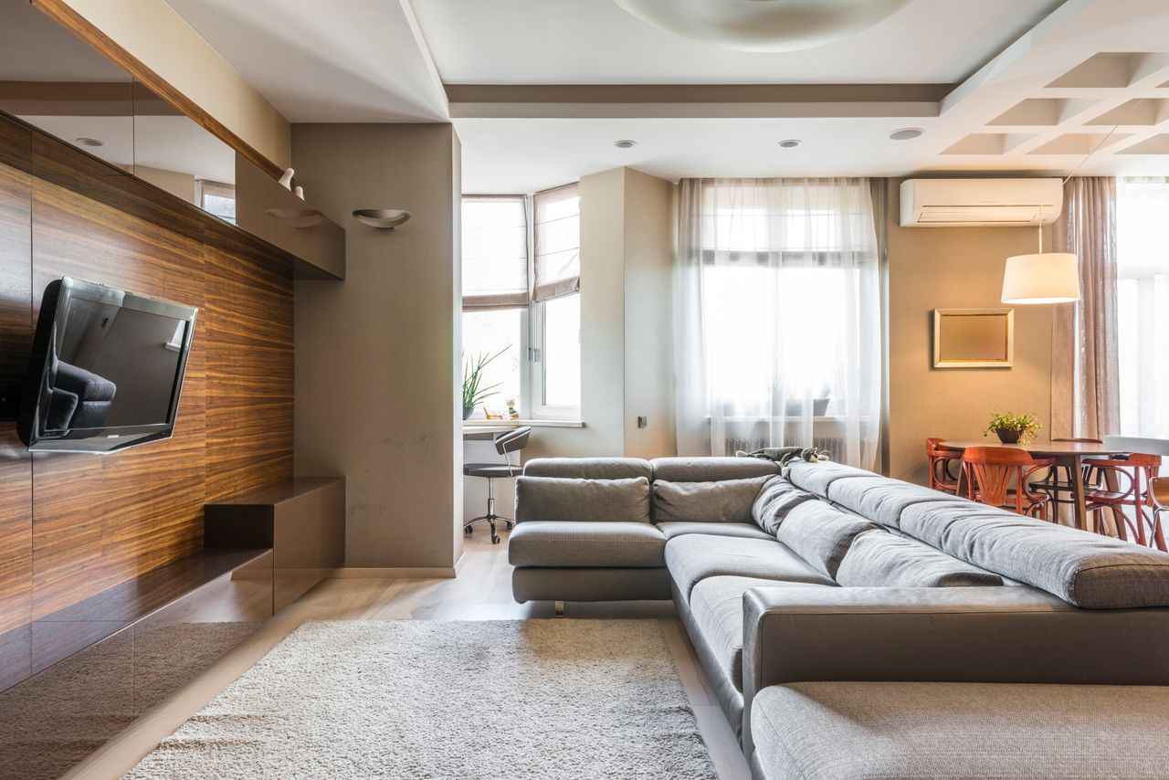 services-01 A cozy and modern living room with a large sofa and natural lighting.